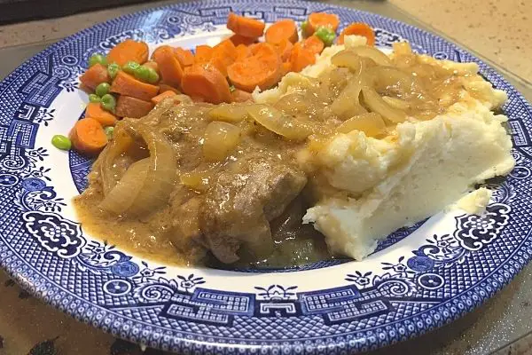 liver and onions with gravy, mashed potatoes, peas and carrots