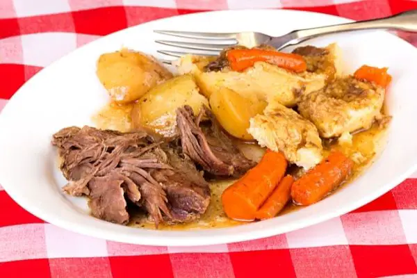 roast with potatoes and carrots on white plate sitting on a red checkered tablecloth for instant pot tri-tip roast recipe