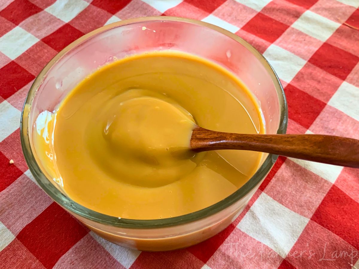 caramel made from sweetened condensed milk in a glass bowl on a red and white checkered tablecloth