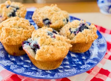 einkorn blueberry muffins with struesel topping on a blue and white plate